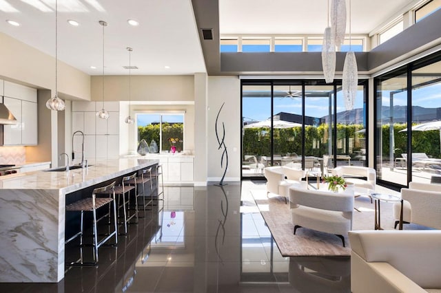 kitchen with a breakfast bar, white cabinetry, light stone counters, a mountain view, and decorative light fixtures