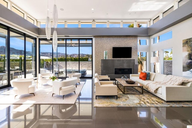 living room featuring a large fireplace, a mountain view, tile patterned flooring, and a towering ceiling