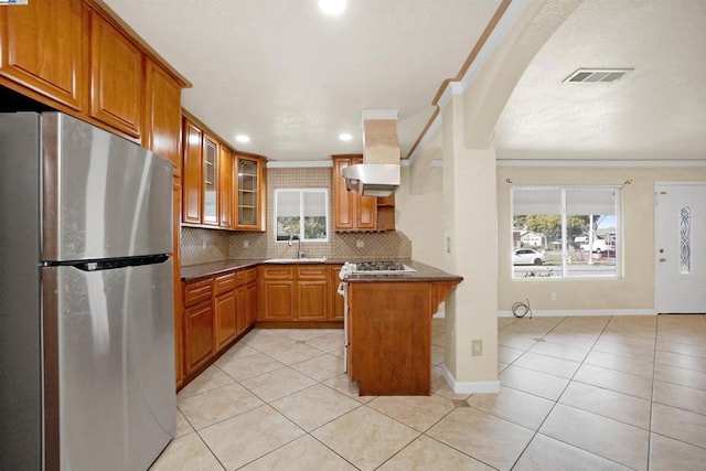 kitchen featuring stainless steel fridge, tasteful backsplash, light tile patterned floors, a kitchen bar, and ornamental molding