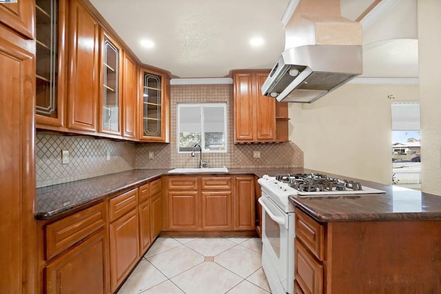 kitchen featuring dark stone countertops, sink, white gas range, island range hood, and light tile patterned flooring