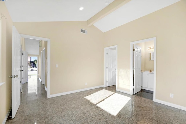 unfurnished bedroom with connected bathroom and lofted ceiling with beams