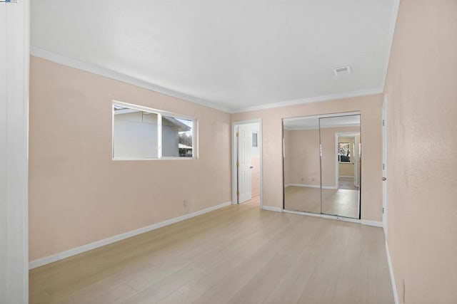 spare room featuring crown molding and light wood-type flooring