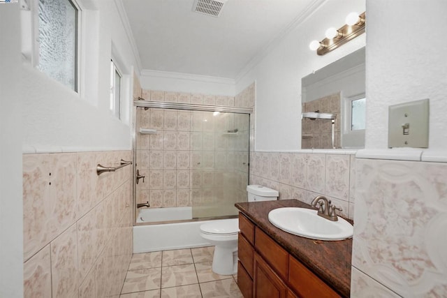 full bathroom with crown molding, tile walls, combined bath / shower with glass door, toilet, and vanity