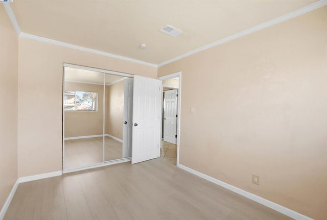 unfurnished bedroom featuring hardwood / wood-style floors, a closet, and ornamental molding