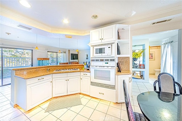 kitchen with a raised ceiling, white appliances, white cabinetry, and pendant lighting