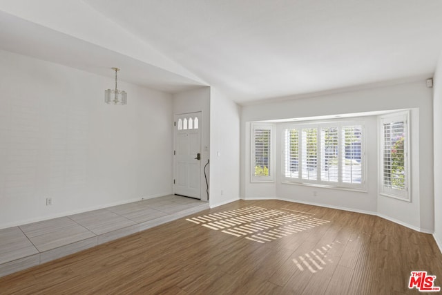 foyer featuring light hardwood / wood-style floors, lofted ceiling, and a notable chandelier