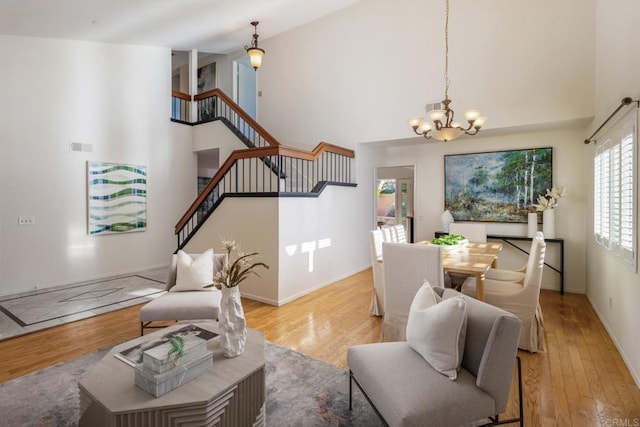 living room featuring light wood-type flooring, a high ceiling, and a chandelier