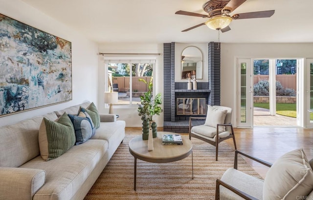 living room with ceiling fan, a fireplace, and light hardwood / wood-style flooring