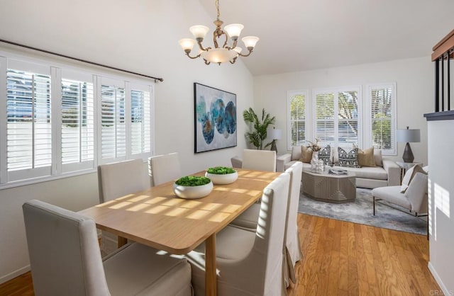 dining area featuring light hardwood / wood-style flooring, a chandelier, and vaulted ceiling