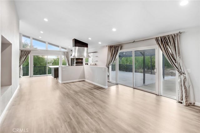 unfurnished living room featuring baseboards, light wood finished floors, vaulted ceiling, and recessed lighting