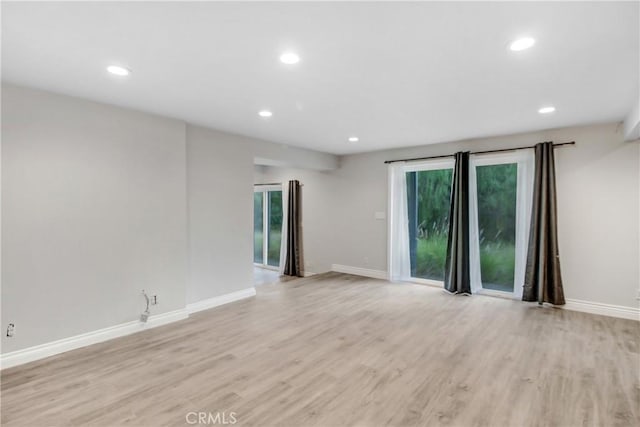 unfurnished room with baseboards, light wood-type flooring, and recessed lighting