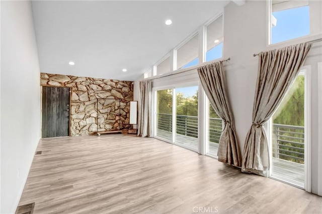 spare room with high vaulted ceiling and light hardwood / wood-style flooring