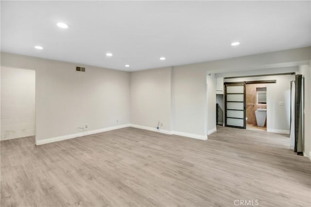 interior space with a barn door and light wood-type flooring