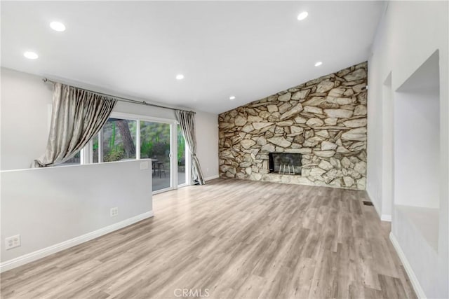 unfurnished living room featuring light hardwood / wood-style flooring and a stone fireplace