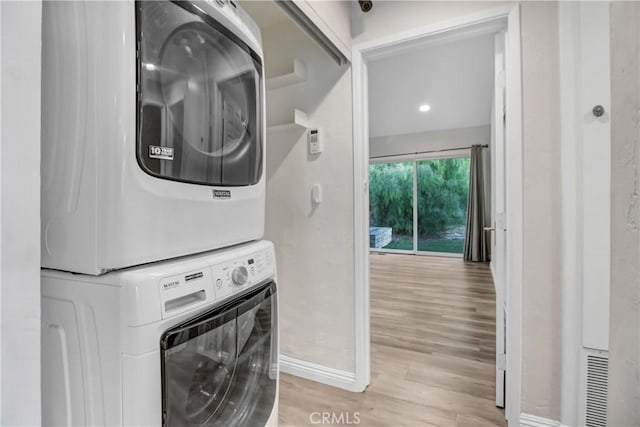 clothes washing area with stacked washer and clothes dryer and light hardwood / wood-style flooring