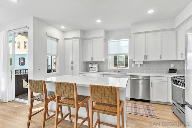 kitchen with white cabinetry, a breakfast bar area, stainless steel appliances, sink, and a center island