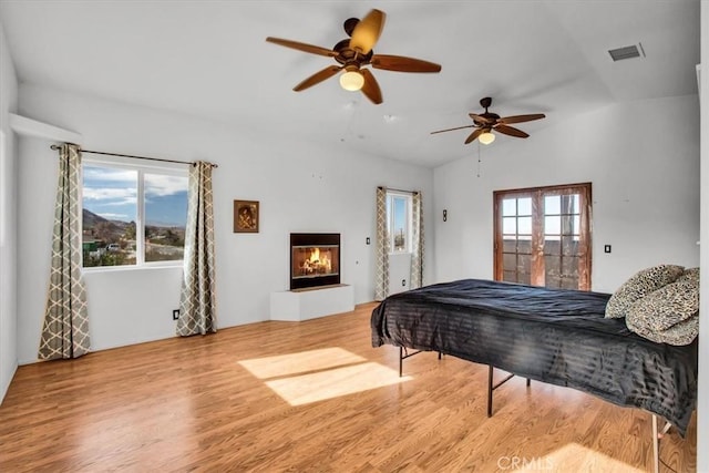 bedroom featuring ceiling fan, light hardwood / wood-style flooring, and lofted ceiling