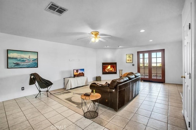 tiled living room featuring ceiling fan and french doors