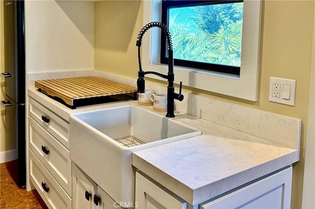 details featuring light countertops, a sink, and white cabinetry