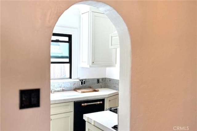 bar with arched walkways, black dishwasher, and decorative backsplash