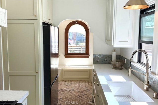 interior space with light countertops, brick floor, a sink, and freestanding refrigerator