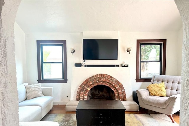 living room featuring a brick fireplace and wood finished floors