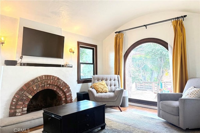 sitting room featuring lofted ceiling, a brick fireplace, and wood finished floors