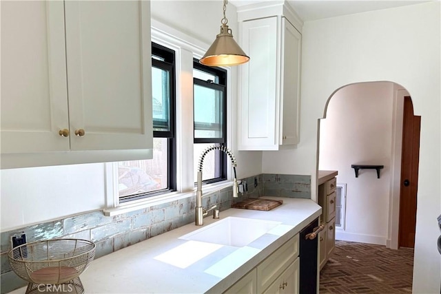 kitchen with brick floor, arched walkways, pendant lighting, and white cabinetry