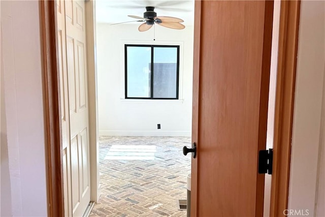 corridor featuring brick floor and baseboards