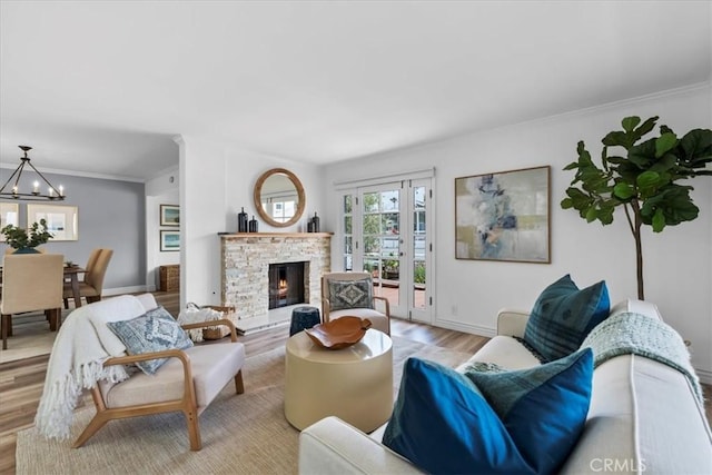 living room featuring a fireplace, light hardwood / wood-style flooring, ornamental molding, an inviting chandelier, and french doors