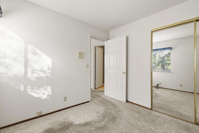 unfurnished bedroom with light colored carpet and a closet