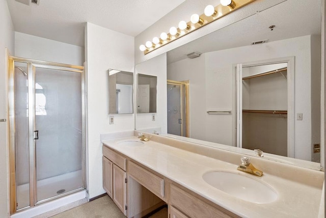 bathroom featuring a shower with shower door and vanity