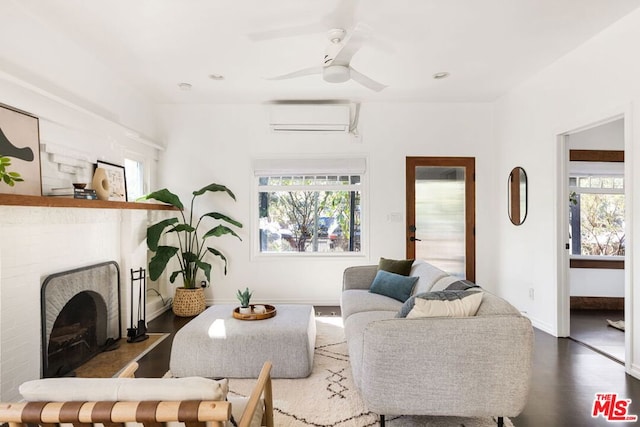 living room with a wall unit AC, a brick fireplace, hardwood / wood-style floors, and ceiling fan