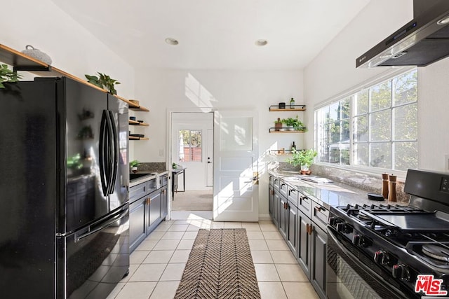 kitchen with black appliances, light tile patterned floors, a healthy amount of sunlight, and range hood