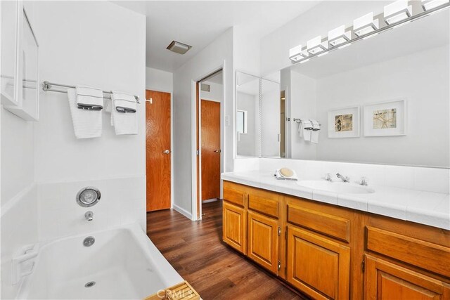 bathroom with a bathing tub, hardwood / wood-style floors, and vanity