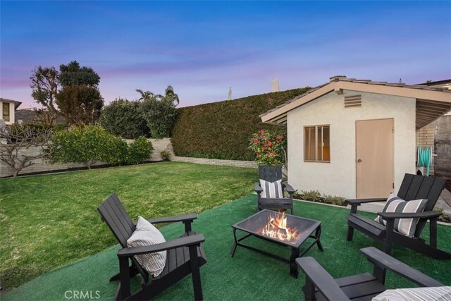 yard at dusk with a fire pit and an outdoor structure