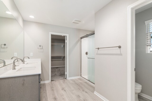 bathroom featuring hardwood / wood-style flooring, an enclosed shower, vanity, and toilet