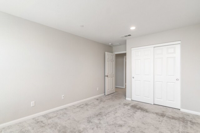 unfurnished bedroom featuring a closet and light colored carpet