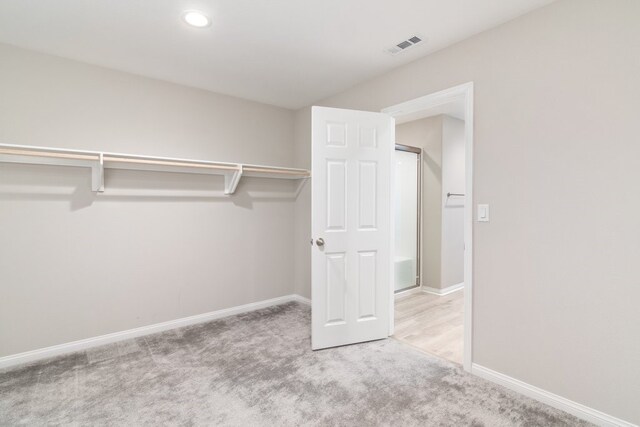 walk in closet featuring light carpet