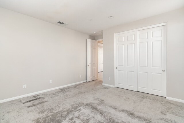 unfurnished bedroom with a closet and light colored carpet