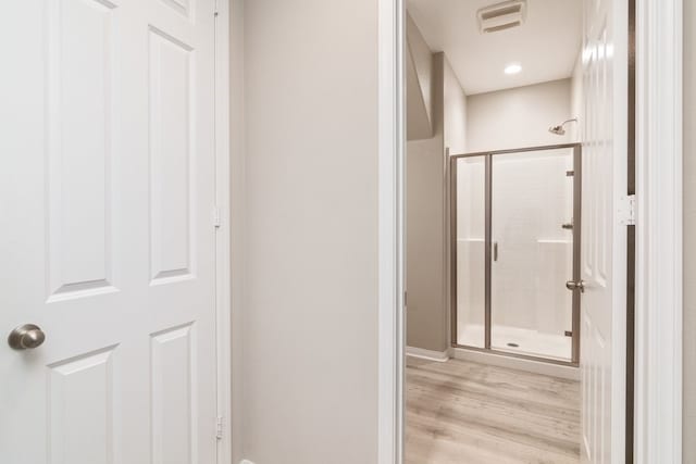 bathroom with hardwood / wood-style flooring and a shower with door