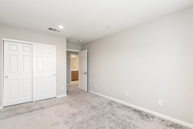 unfurnished bedroom with a closet and light carpet