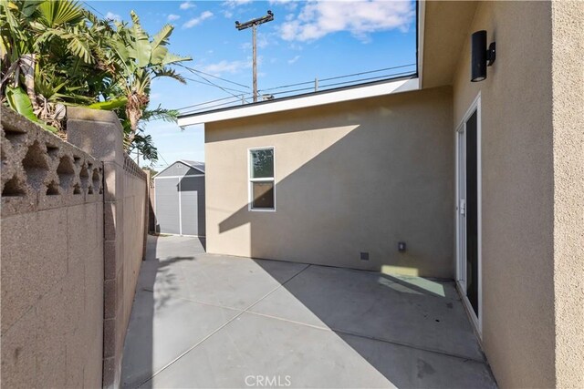 view of side of property with a storage shed and a patio