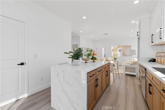 kitchen featuring dishwasher, white cabinetry, light hardwood / wood-style flooring, and a kitchen island