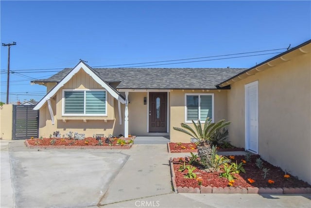 ranch-style house featuring a shingled roof and stucco siding