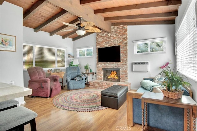 living room featuring an AC wall unit, light hardwood / wood-style floors, a wealth of natural light, and vaulted ceiling with beams