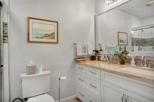 bathroom featuring toilet, a shower with shower door, and vanity