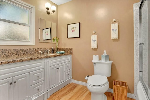 full bathroom featuring toilet, vanity, shower / bath combination with glass door, and hardwood / wood-style flooring