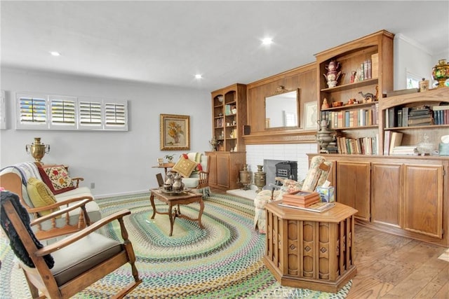 sitting room with crown molding, a wood stove, and light hardwood / wood-style flooring