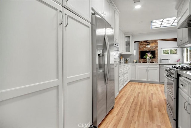 kitchen featuring white cabinets, stainless steel appliances, light hardwood / wood-style floors, kitchen peninsula, and ceiling fan